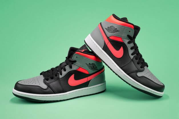 The Nike Air Jordan 1 in black/grey on a green background