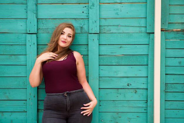 a beautiful plus sized model stands by fence