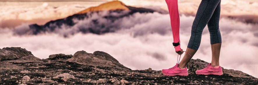 a woman ties up her running shoes by the sea