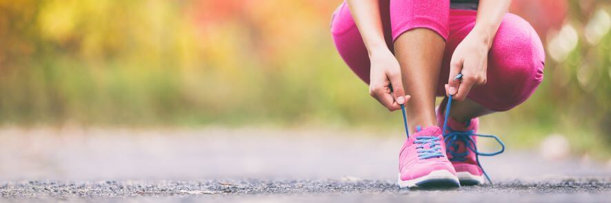 Woman ties up her long distance running shoes ready for a race